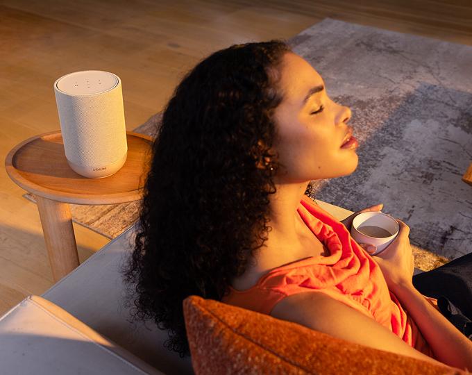 Denon Home 200 wireless speaker in white on a cabinet in a home setting